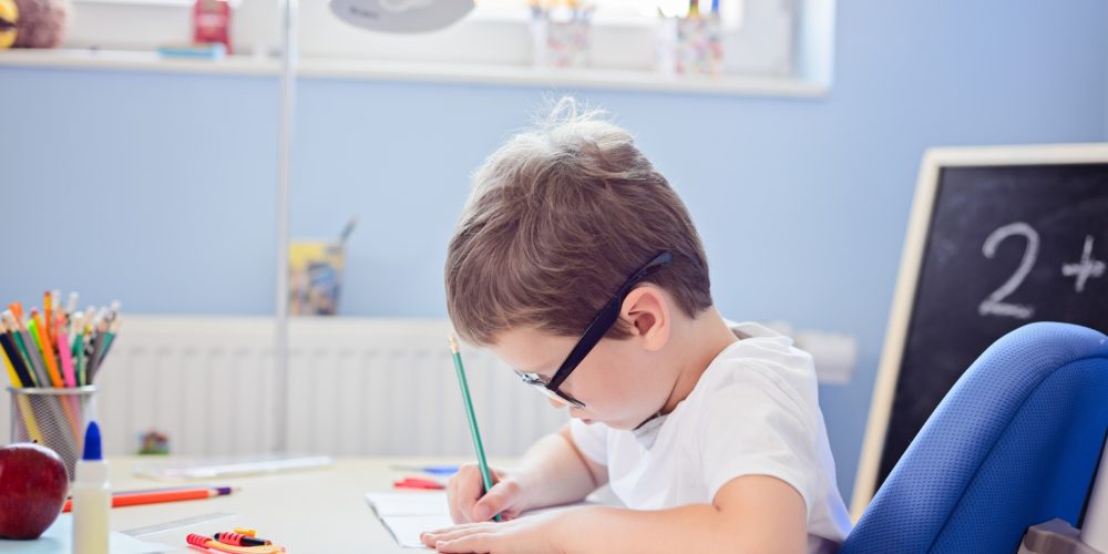 圖片顯示一個男孩在書桌上寫作