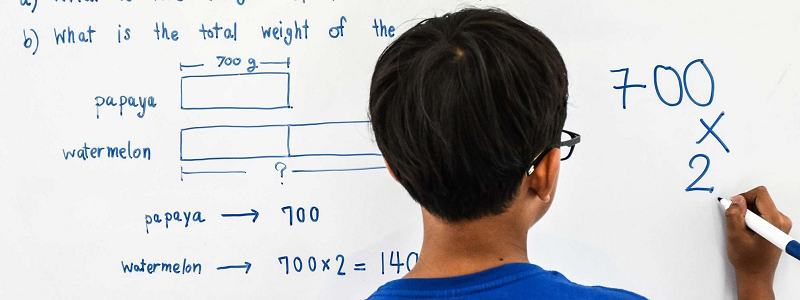 圖片顯示男孩解決數學問題在白板上
